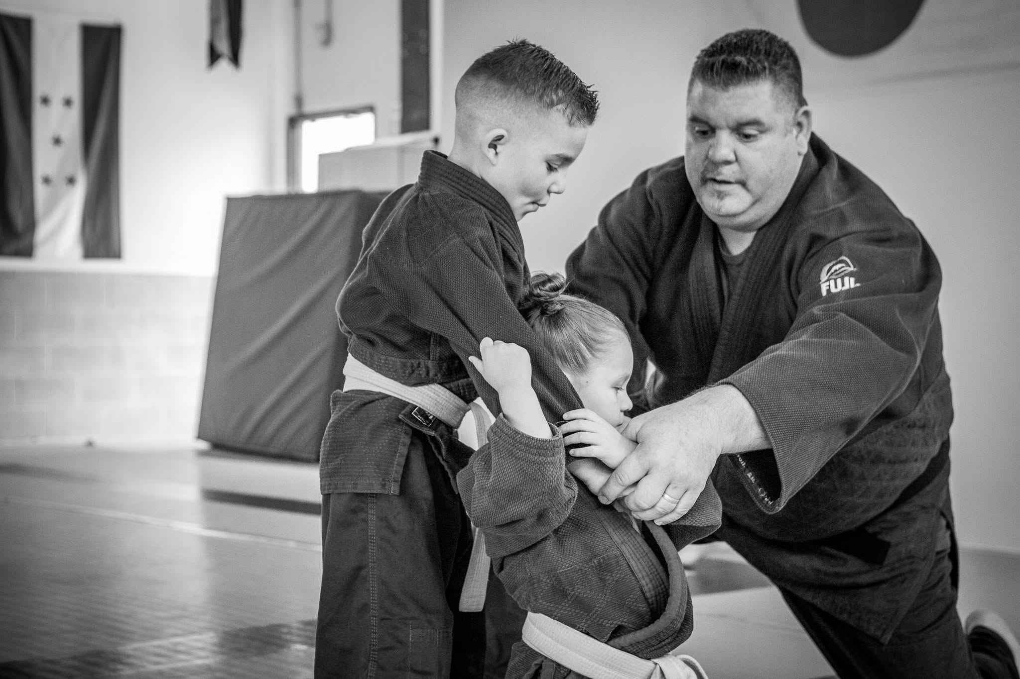 A coach helping young judo students practice safely