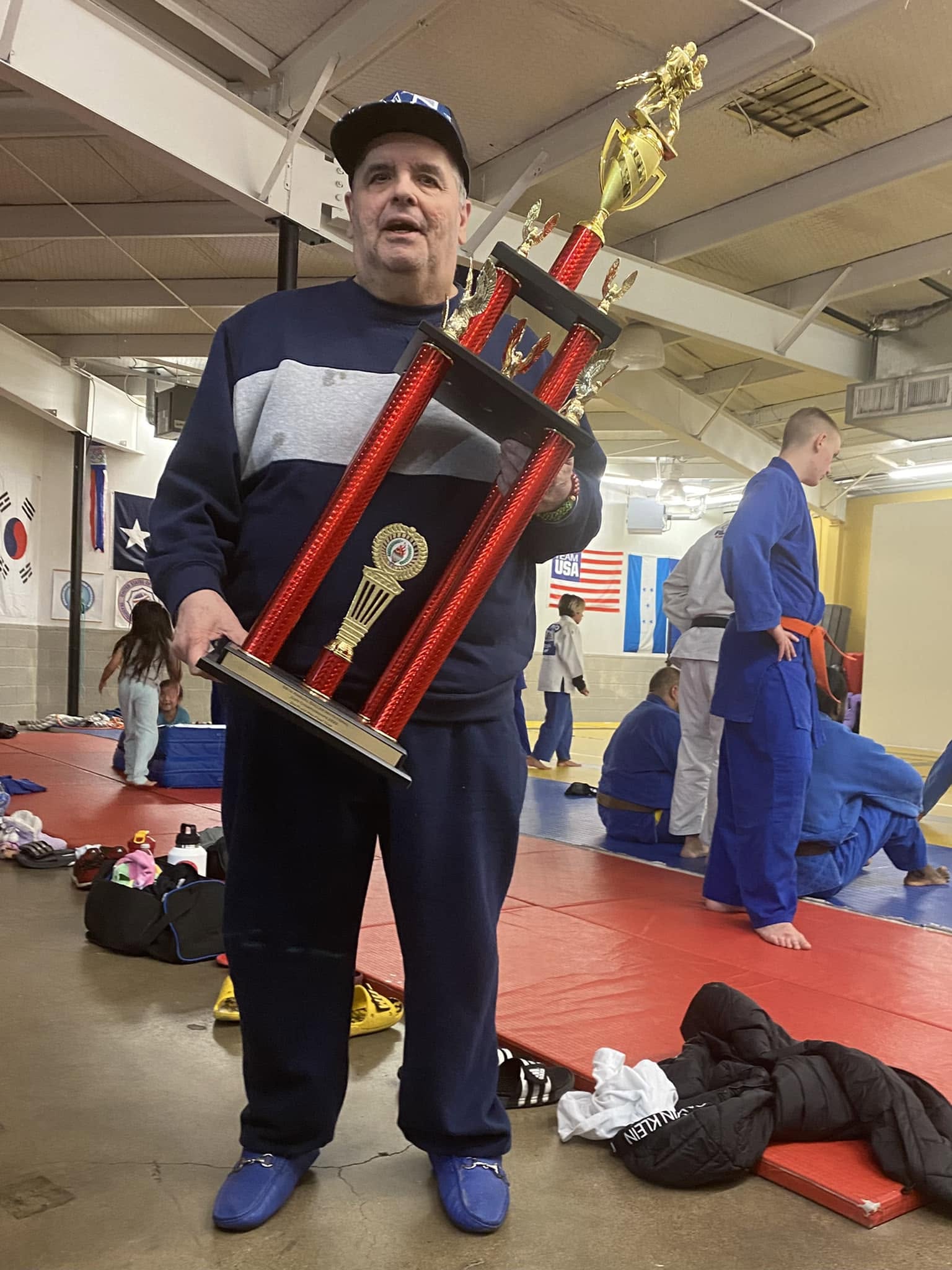 A Becerra Judo member holding a large competition trophy